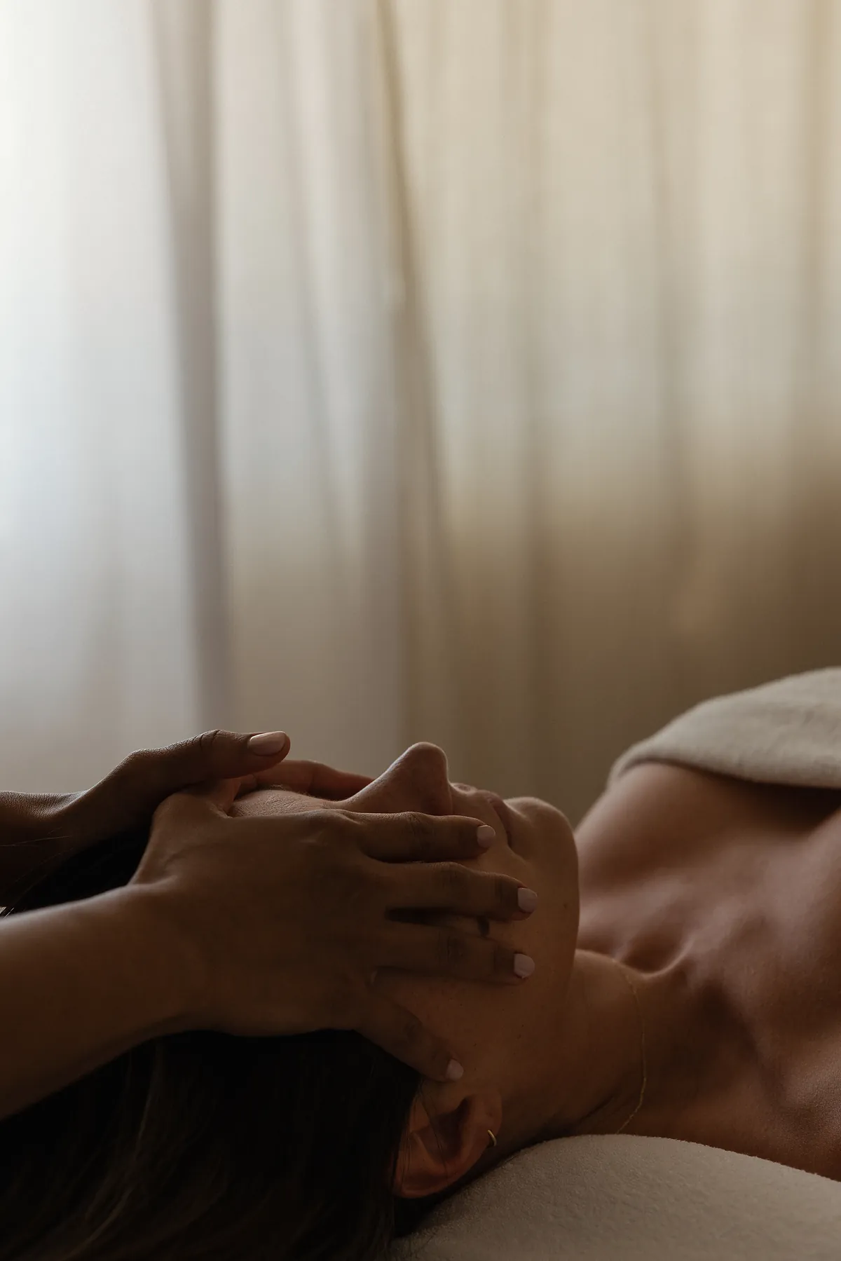 A therapist cradling a client’s face during a facial treatment