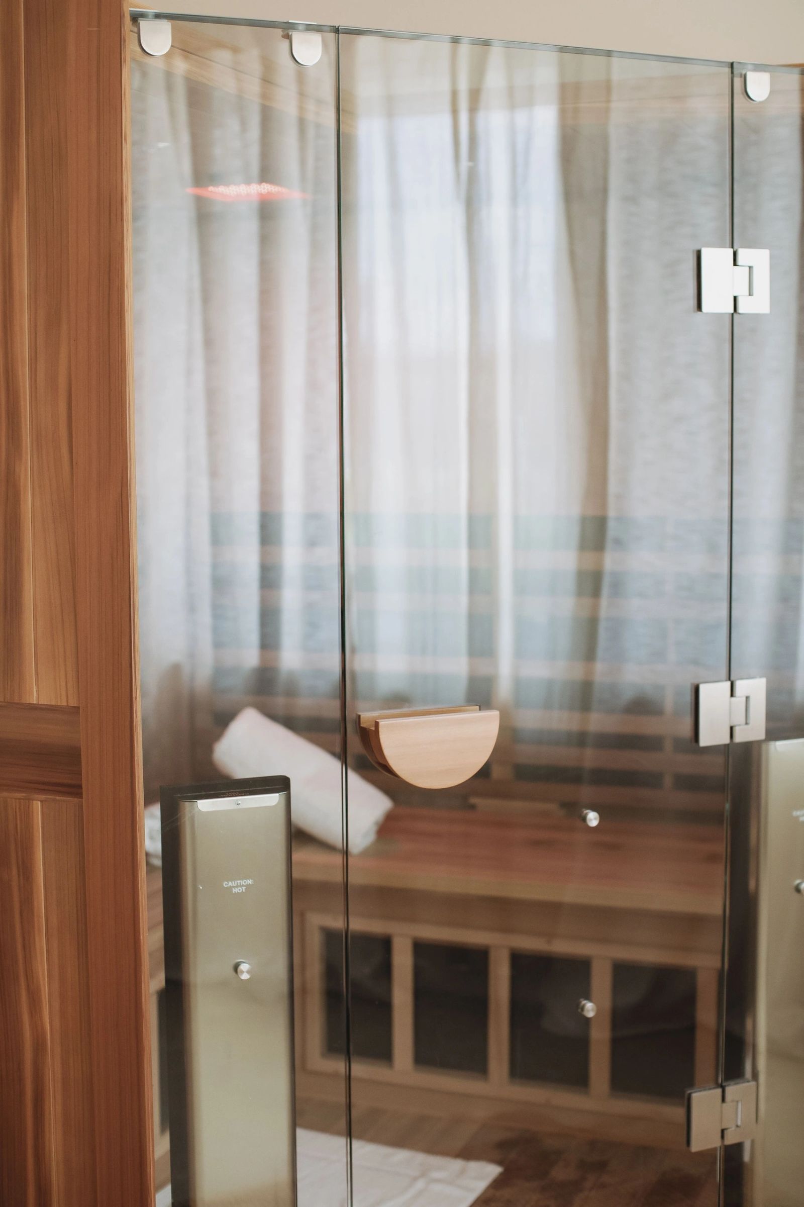 The glass door of a full spectrum infrared sauna cabin at Mesa, timber bench inside